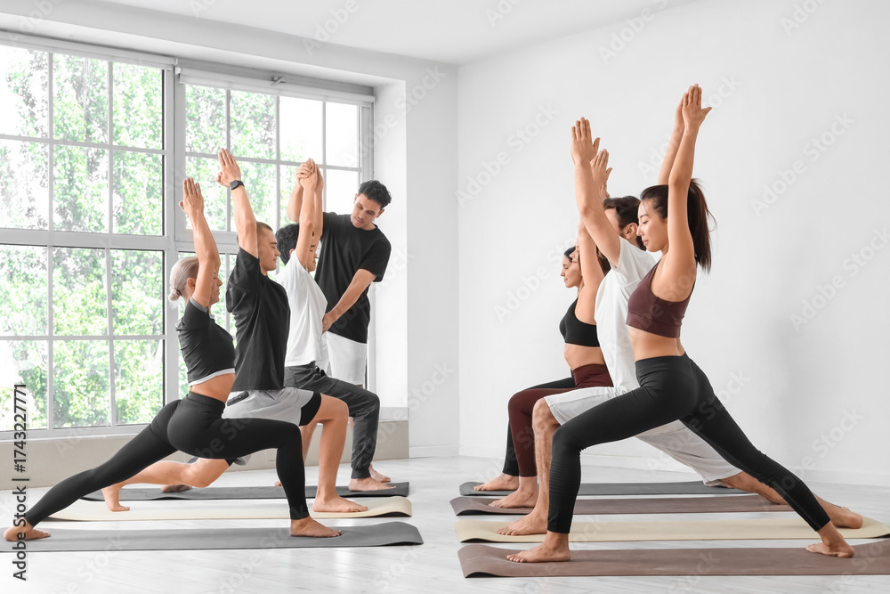 Obraz premium Group of sporty young people practicing yoga at gym