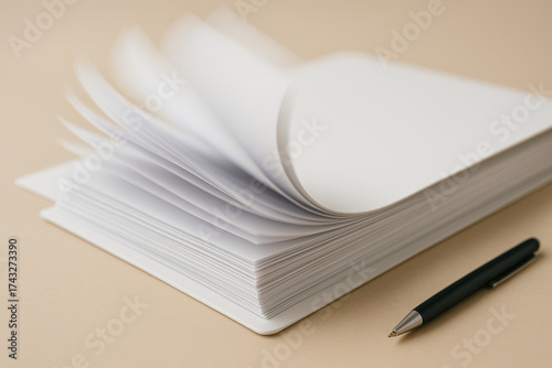 Open notebook with blank white pages and black pen on beige background, concept of writing, education, creativity, note taking