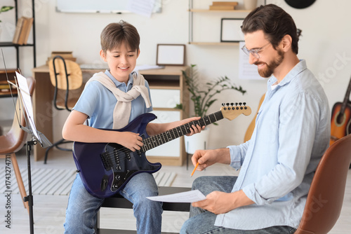 Cute boy taking guitar less...