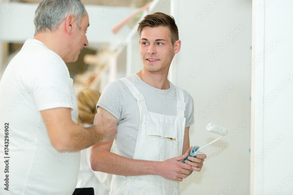 Fototapeta premium painter teaching roller technique to apprentice decorator