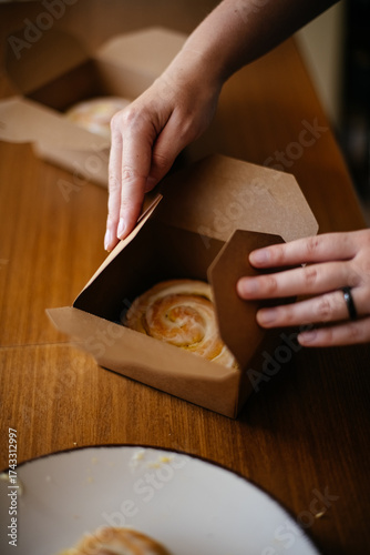 Hands closing bakery box with roll
