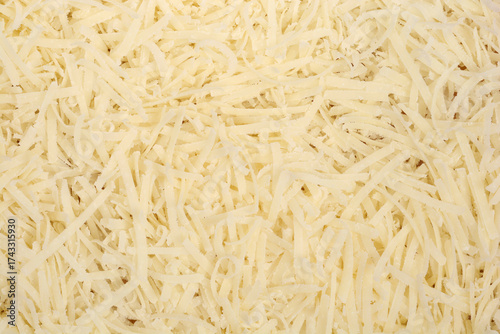 A detailed close-up shot shows a textured background completely filled with shredded yellow Parmesan cheese