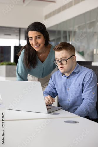 Hispanic mentor checking work result of employee with Down syndrome