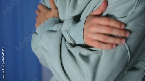 A man in a warm sweater warms himself with his hands from the cold.
A man is shivering from the cold.
Winter and cold.