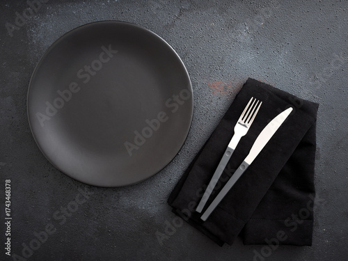 Empty black plate cutlery on dark background