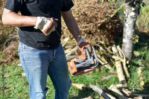 Φωτογραφία Homme coupant du bois à la tronçonneuse dans le jardin, travail manuel en automn