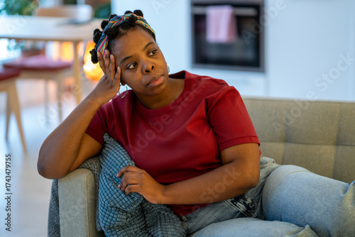 Cuadro en lienzo Pensive frustrated black woman sitting on sofa at home feeling uneasy, distracted