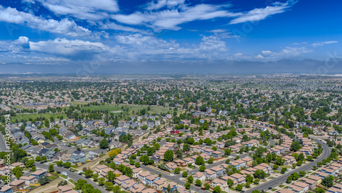 Aerial view of a suburban landscape unfolds under a bright sky, with houses and green spaces creating a tapestry of urban life, Denver, Colorado, United States.