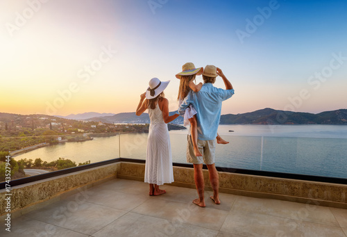 A family on summer holidays enjoys the beautiful, panoramic sunset view from their terrace over the mediterranean sea