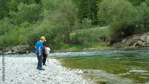 Dad and son throwing stones into the river, family time in nature.