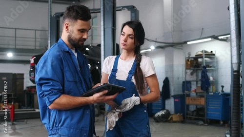 Digital tablet is in hands. Auto repair shop employees are working together. Man and woman