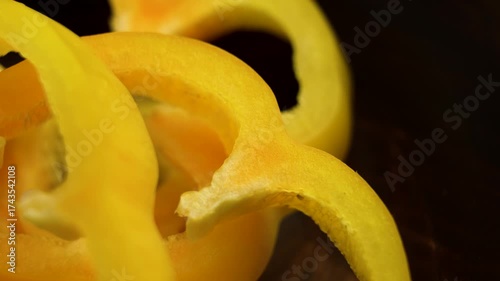 Sliced juicy yellow bell peppers in a wooden bowl. Macro view. Rotation