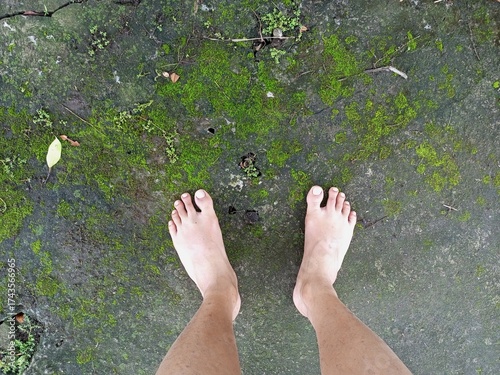 Bare Feet Standing On Green Mossy Concrete Outdoors