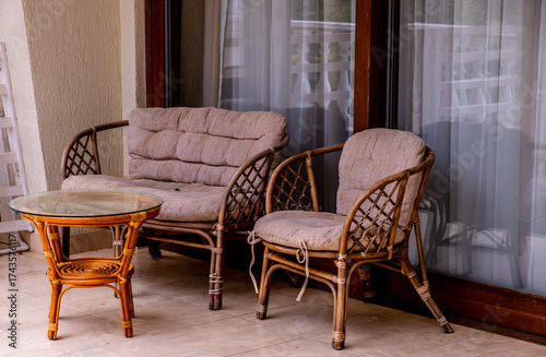 A sofa with an armchair on the veranda of the house.