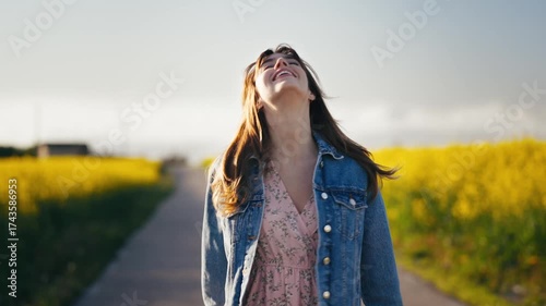 Smiling woman strolls through blooming yellow rape fields