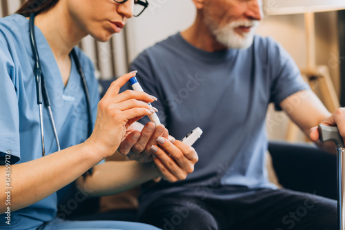 Nurse checking senior man's blood sugar level at home, selective focus on hands