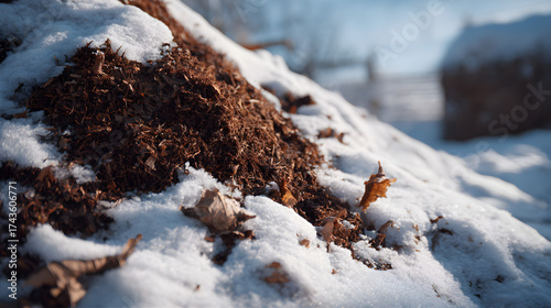 Snow-covered mulch pile in winter garden setting  