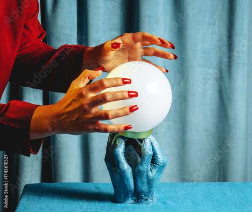 Woman in red using a crystal ball for fortune telling indoors