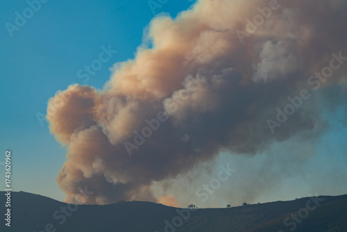 Large Smoke Plume Rising Over Scenic Landscape