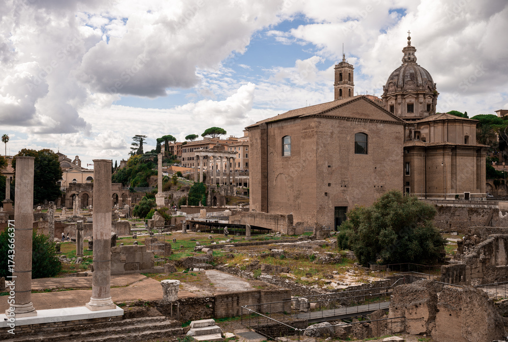 Obraz premium Ancient Roman ruins and historical buildings under dramatic cloudy sky in Rome