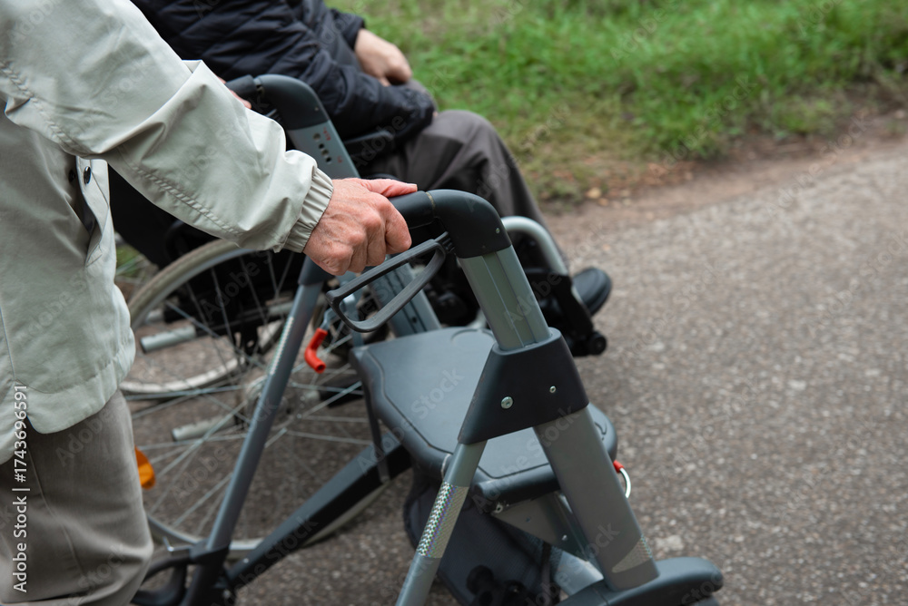 Obraz premium Elderly friends taking a walk in the park during cold weather with help of wheelchair and walker enjoying and having fun