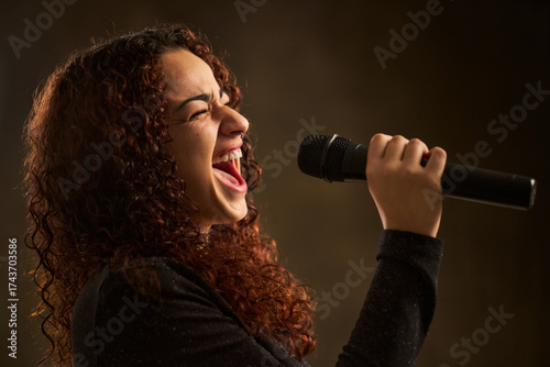Woman singer passionately performing vocal music with microphone