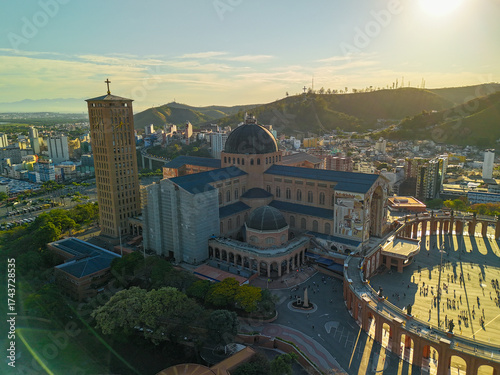 aerial view of the Basilica of the National Shrine of Our Lady Aparecida in Brazil during sunrise with mountains and greenery at distance