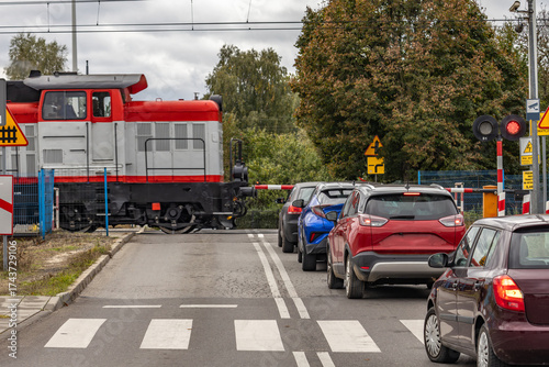Cars waiting at a railway crossing with a passing freight train