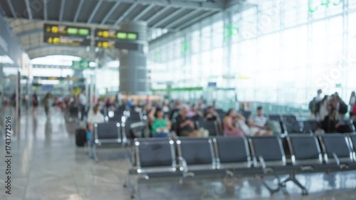 Blurred view of people waiting in an airport terminal with defocused backgrounds and bokeh lighting that highlights a travel-focused environment.