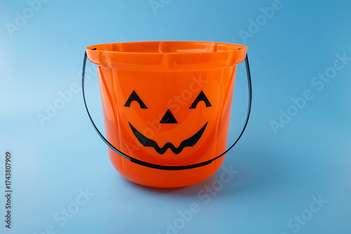 Foto Orange plastic pumpkin bucket with black handle on blue background