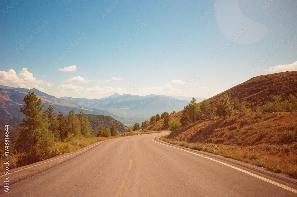 Fototapeta premium Curvy mountain pathway under a clear summer sky with trees and scenic views