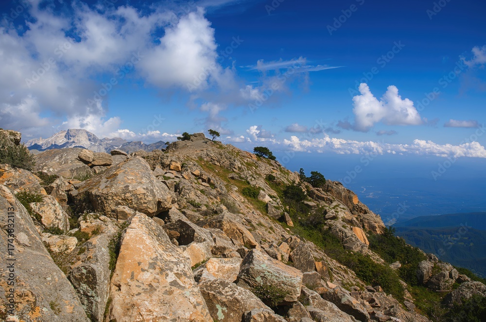 Fototapeta premium Rocky Hill Under a Clear Blue Sky with Puffy White Clouds