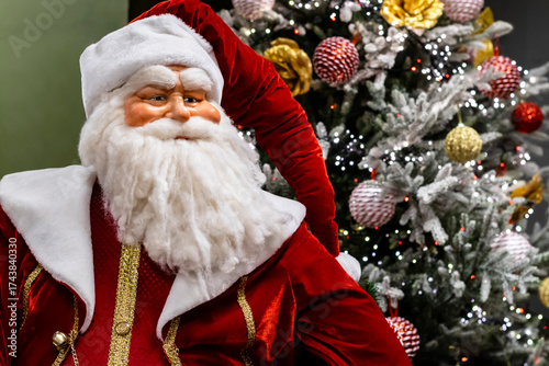 Santa Claus doll close-up against a beautifully decorated Christmas tree with festive lights, selective focus