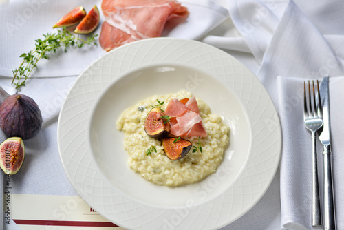 risotto with figs and ham in a white plate on the table
