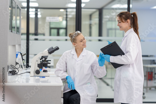 Lab technicians collaborate in a modern laboratory while discussing findings and using advanced equipment
