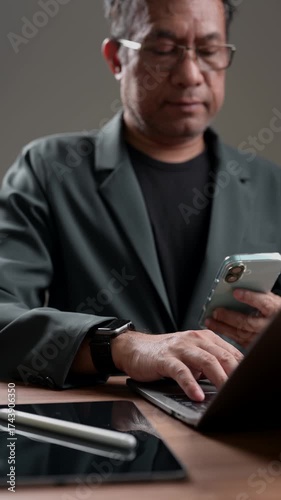 Professional executive works remotely, managing business tasks using multiple modern digital devices. Dedicated businessman multitasking, focused productivity. Technology integration streamlines