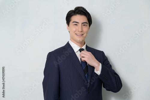 白背景でカメラ目線のスーツの日本人男性