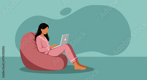 Relaxed woman in pajamas uses laptop from a comfortable bean bag chair remote work concept