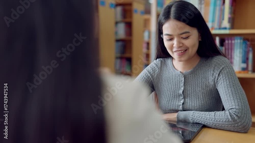 Asian female student getting guidance in academic counseling session with advisor at university setting with documents and tablet.