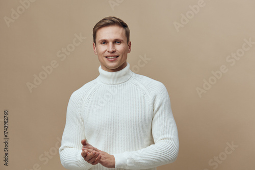 Bild auf Leinwand Smiling man wearing white knitted turtleneck sweater, looking at camera, isolate