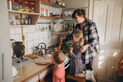 Behang Mother preparing food with children in kitchen