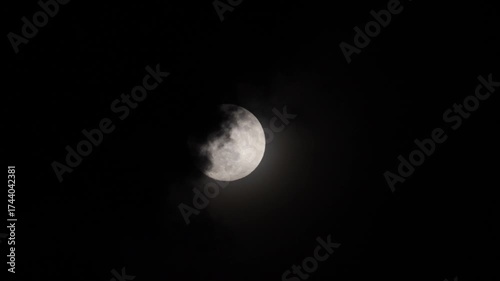 The silver light of the moon is swallowed by gathering storm clouds.