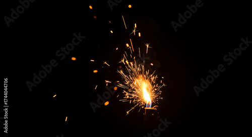 Fiery sparkler bursting brightly with golden sparks flying outward