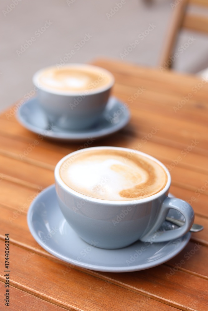 Fototapeta premium Cups of aromatic coffee on wooden table, closeup