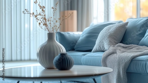 Elegant living room with blue tones and soft cushions- featuring a cozy throw and modern vase on a coffee table. Relaxing interior design.