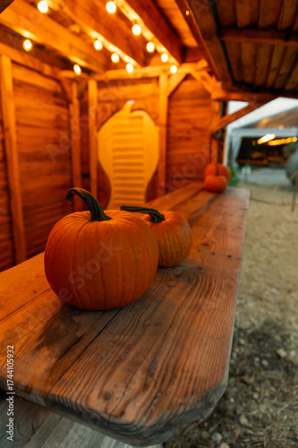 Two pumpkins placed on a wooden stand under warm light, creating a cozy Halloween atmosphere.