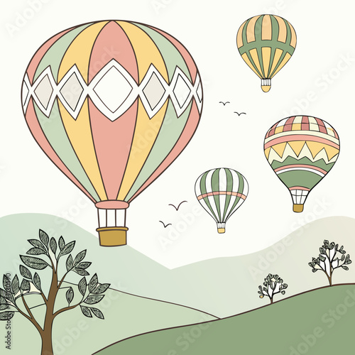 Four colorful hot air balloons floating over rolling green hills and trees