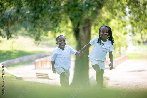 Playful brother hugging sister outdoors in park during carefree joyful summer sunny afternoon