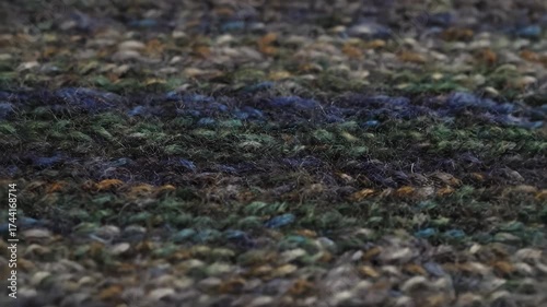 Close-up of a knitted fabric with a colorful, textured pattern, showcasing the intricate weaving of various yarn colors.