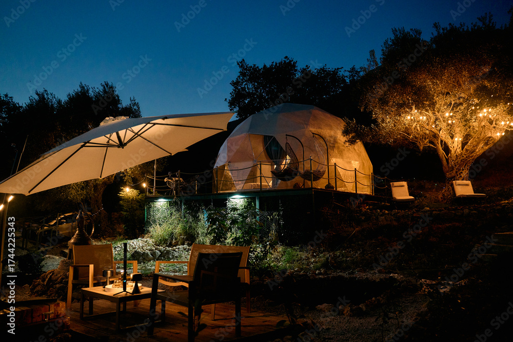 Fototapeta premium Charming Outdoor Glamping Retreat at Night Surrounded by Nature with Cozy Lighting and Comfortable Seating for Relaxation